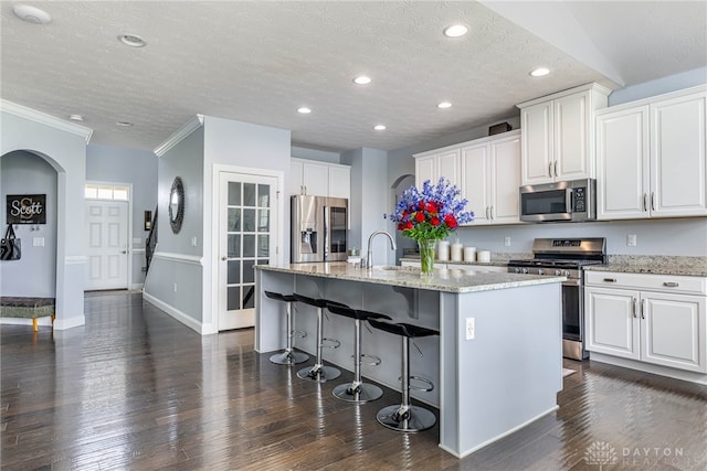 9282 Maple Brook St, Clearcreek Twp, OH 45458 - kitchen featuring appliances with stainless steel finishes, an island with sink, dark wood-type flooring, light stone countertops, and a textured ceiling