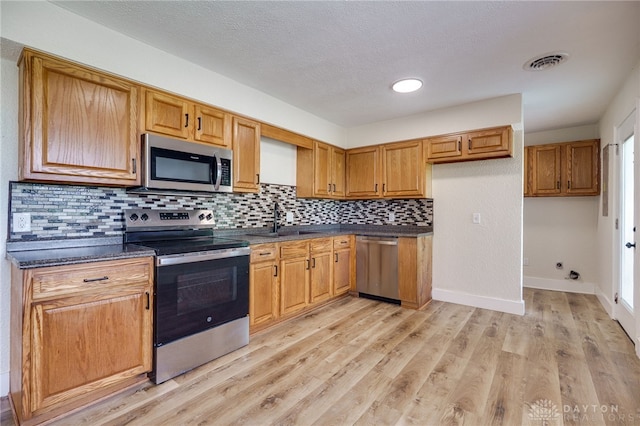 3183 Myers Tillman Rd, Arcanum, OH 45304 - kitchen featuring stainless steel appliances, dark countertops, tasteful backsplash, light wood-type flooring, and brown cabinets