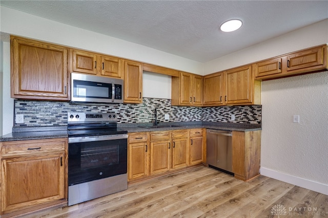 3183 Myers Tillman Rd, Arcanum, OH 45304 - kitchen with stainless steel appliances, dark countertops, decorative backsplash, brown cabinetry, and a textured ceiling