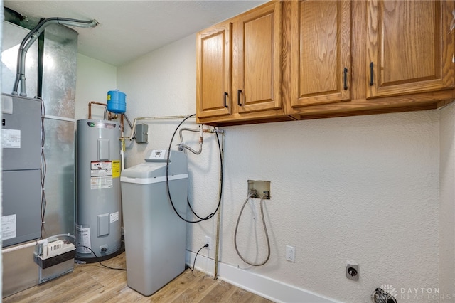 3183 Myers Tillman Rd, Arcanum, OH 45304 - washroom featuring electric water heater, cabinet space, light wood-type flooring, hookup for a washing machine, and a textured wall