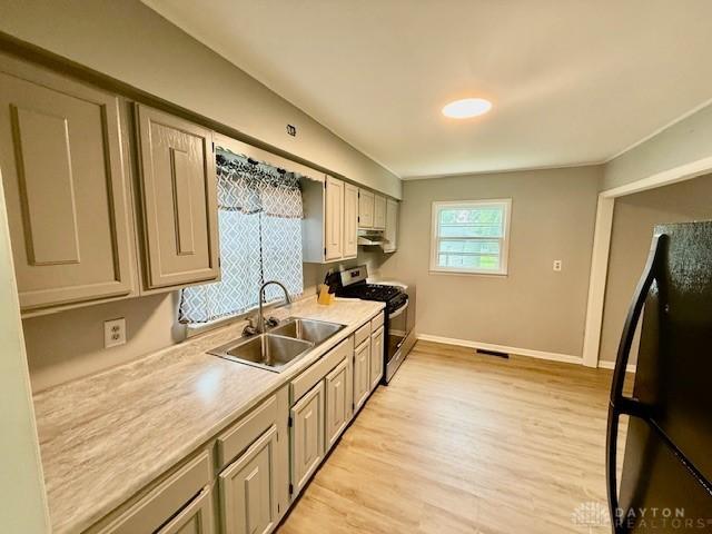 135 B St, Wilmington, OH 45177 - kitchen featuring stainless steel gas range oven, freestanding refrigerator, light countertops, light wood finished floors, and under cabinet range hood
