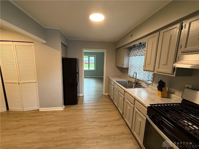 135 B St, Wilmington, OH 45177 - kitchen featuring stainless steel range with gas stovetop, freestanding refrigerator, under cabinet range hood, light countertops, and light wood-type flooring
