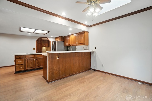 3820 Shagbark Ln, Beavercreek, OH 45440 - kitchen with freestanding refrigerator, a peninsula, light wood-style flooring, a ceiling fan, and crown molding