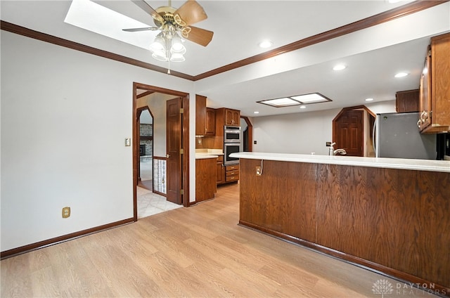 3820 Shagbark Ln, Beavercreek, OH 45440 - kitchen featuring ceiling fan, light countertops, light wood-style flooring, crown molding, and a peninsula