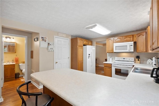 5431 Flicker Way, Dayton, OH 45424 - kitchen featuring white appliances, a peninsula, light wood-type flooring, light countertops, and a kitchen bar