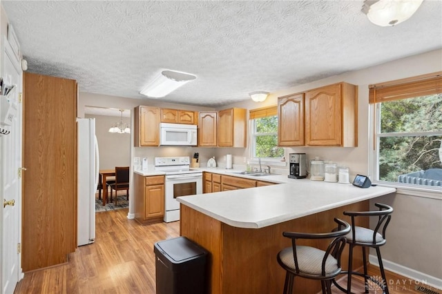 5431 Flicker Way, Dayton, OH 45424 - kitchen featuring white appliances, a peninsula, light wood finished floors, light countertops, and a breakfast bar