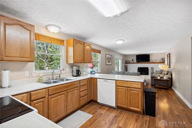 5431 Flicker Way, Dayton, OH 45424 - kitchen with white dishwasher, dark wood finished floors, a peninsula, a fireplace, and a textured ceiling