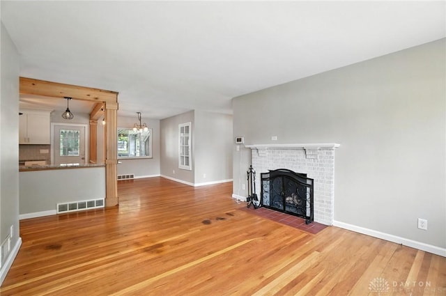 4503 Central Ave, Middletown, OH 45044 - unfurnished living room featuring light wood finished floors, a brick fireplace, and a chandelier