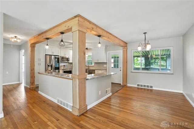 4503 Central Ave, Middletown, OH 45044 - kitchen featuring stainless steel appliances, white cabinets, light wood-style floors, light stone counters, and a chandelier
