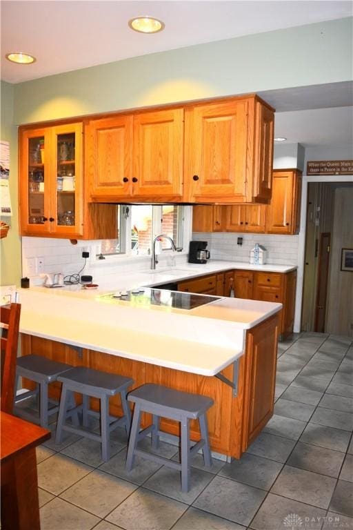 3235 W Ziegler Rd, Piqua, OH 45356 - kitchen with a breakfast bar area, light countertops, backsplash, brown cabinets, and recessed lighting