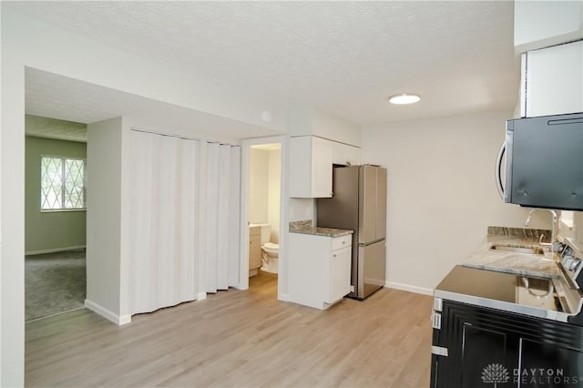 9446 Haddington Ct Unit 200, Cincinnati, OH 45251 - kitchen featuring freestanding refrigerator, light wood-style floors, white cabinets, a textured ceiling, and light countertops