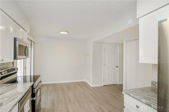 9446 Haddington Ct Unit 200, Cincinnati, OH 45251 - kitchen featuring appliances with stainless steel finishes, light wood-style flooring, white cabinets, light stone counters, and a textured ceiling