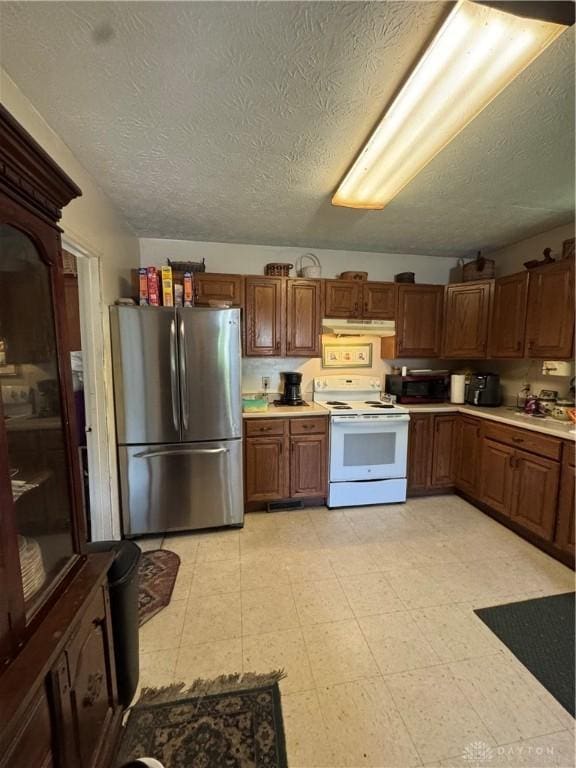 8211 Sue Ave, Franklin, OH 45005 - kitchen featuring freestanding refrigerator, electric stove, under cabinet range hood, light countertops, and brown cabinetry