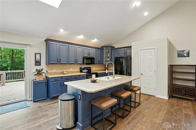 2210 Hidden Woods Blvd, Beavercreek, OH 45431 - kitchen with black appliances, light wood-style floors, light countertops, decorative backsplash, and lofted ceiling