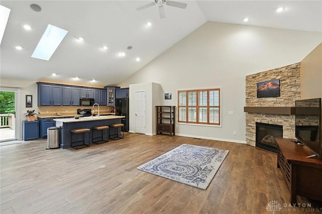 2210 Hidden Woods Blvd, Beavercreek, OH 45431 - kitchen featuring black appliances, open floor plan, light countertops, high vaulted ceiling, and a center island with sink