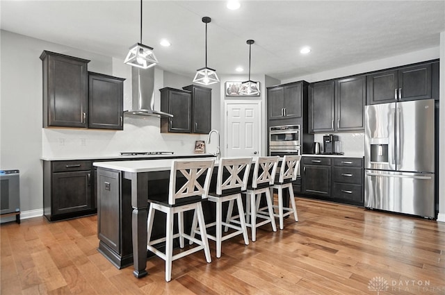 539 Bellasera Dr, Sugarcreek Twp, OH 45440 - kitchen with stainless steel appliances, wall chimney range hood, backsplash, light wood-style flooring, and light countertops