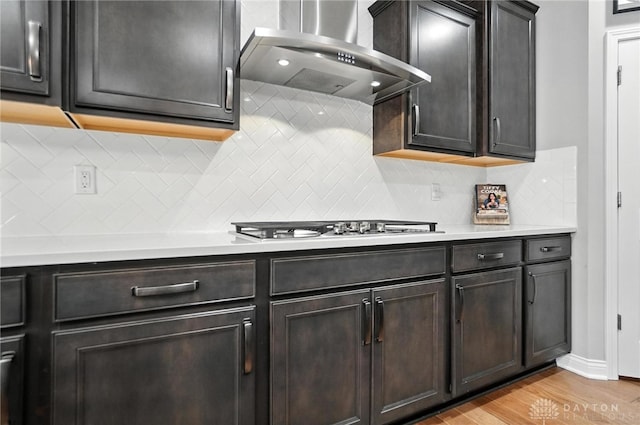 539 Bellasera Dr, Sugarcreek Twp, OH 45440 - kitchen with wall chimney exhaust hood, light countertops, light wood-type flooring, white gas stovetop, and tasteful backsplash