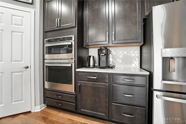 539 Bellasera Dr, Sugarcreek Twp, OH 45440 - kitchen with stainless steel appliances, backsplash, light countertops, light wood-style floors, and dark brown cabinets