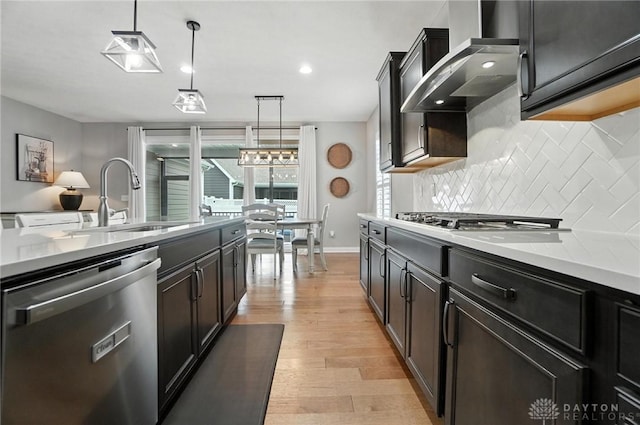 539 Bellasera Dr, Sugarcreek Twp, OH 45440 - kitchen with appliances with stainless steel finishes, wall chimney exhaust hood, backsplash, light wood finished floors, and light countertops