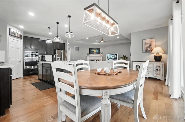 539 Bellasera Dr, Sugarcreek Twp, OH 45440 - dining space with light wood-type flooring, recessed lighting, ceiling fan, and a fireplace