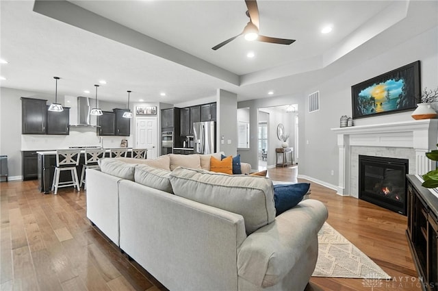 539 Bellasera Dr, Sugarcreek Twp, OH 45440 - living area featuring ceiling fan, recessed lighting, wood finished floors, a glass covered fireplace, and a raised ceiling