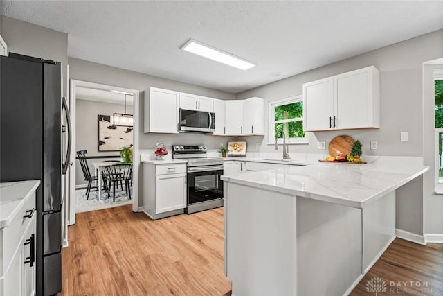 4182 Fox Fern Ct, Beavercreek, OH 45432 - kitchen featuring appliances with stainless steel finishes, light wood-type flooring, a peninsula, white cabinets, and light stone countertops