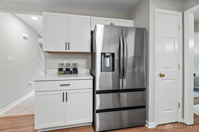 4182 Fox Fern Ct, Beavercreek, OH 45432 - kitchen with stainless steel refrigerator with ice dispenser, white cabinetry, light countertops, recessed lighting, and light wood-type flooring