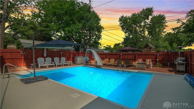 429 Rader Dr, Vandalia, OH 45377 - pool at dusk with a water slide, grilling area, a patio area, and a fenced backyard