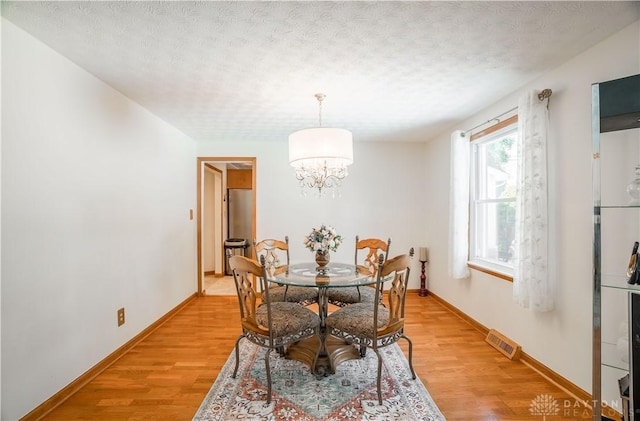 429 Rader Dr, Vandalia, OH 45377 - dining space featuring a textured ceiling, light wood-style floors, and a chandelier