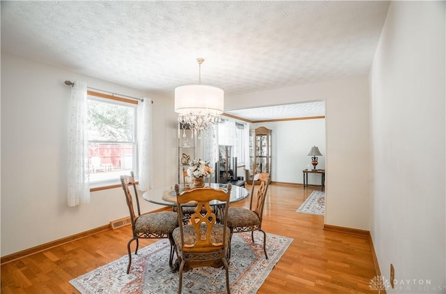429 Rader Dr, Vandalia, OH 45377 - dining area with light wood-style flooring, a chandelier, and a textured ceiling