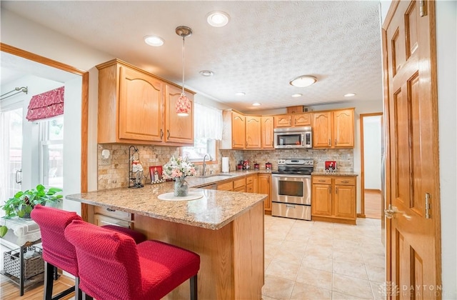 429 Rader Dr, Vandalia, OH 45377 - kitchen featuring stainless steel appliances, a peninsula, backsplash, a breakfast bar, and light stone counters