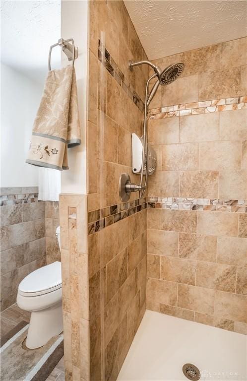 429 Rader Dr, Vandalia, OH 45377 - bathroom with a stall shower, tile walls, a wainscoted wall, and a textured ceiling