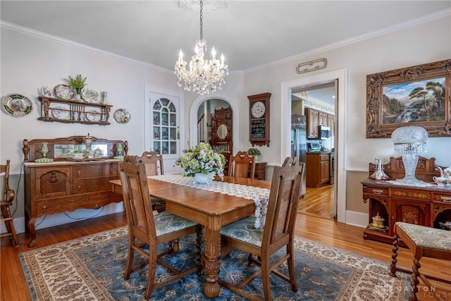 288 N King St, Xenia, OH 45385 - dining area featuring wood finished floors, a chandelier, crown molding, and arched walkways