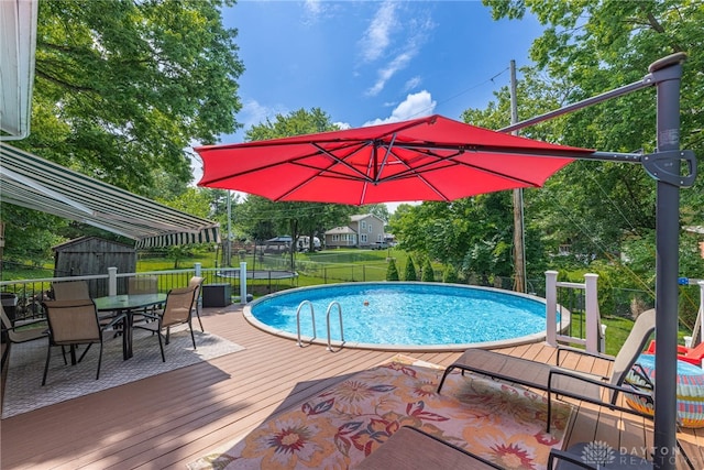 288 N King St, Xenia, OH 45385 - swimming pool with a trampoline, a storage shed, outdoor dining space, a wooden deck, and a fenced backyard
