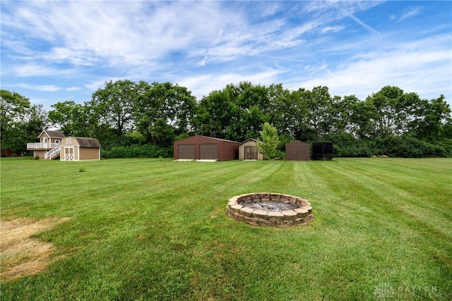 4095 N State Route 42, Waynesville, OH 45068 - view of green lawn with a storage shed, a fire pit, view of scattered trees, and a detached garage