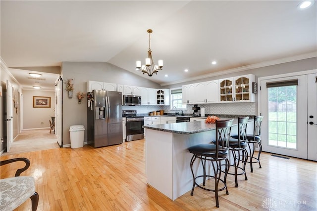 4095 N State Route 42, Waynesville, OH 45068 - kitchen featuring appliances with stainless steel finishes, glass insert cabinets, a breakfast bar area, lofted ceiling, and white cabinetry