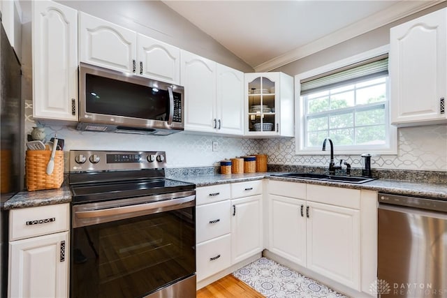 4095 N State Route 42, Waynesville, OH 45068 - kitchen featuring stainless steel appliances, dark countertops, vaulted ceiling, glass insert cabinets, and white cabinetry