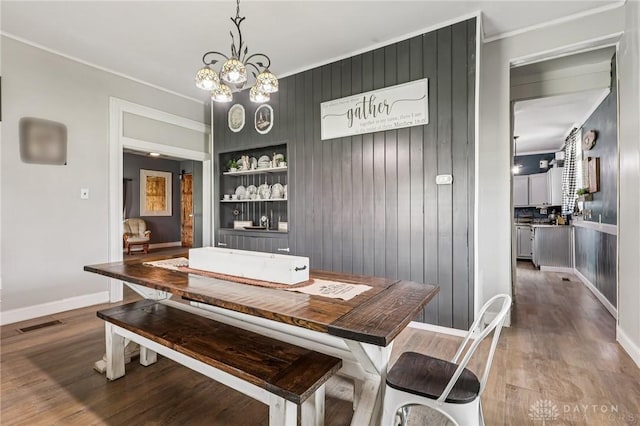 213 N Broadway St, Blanchester, OH 45107 - dining space featuring wood finished floors, ornamental molding, built in features, and a chandelier