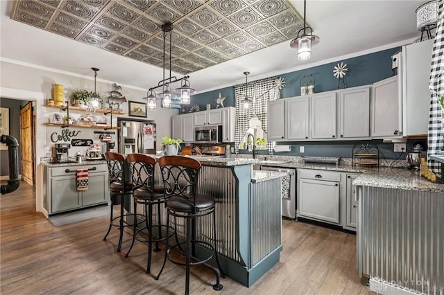 213 N Broadway St, Blanchester, OH 45107 - kitchen featuring appliances with stainless steel finishes, wood finished floors, light stone countertops, a kitchen bar, and a kitchen island