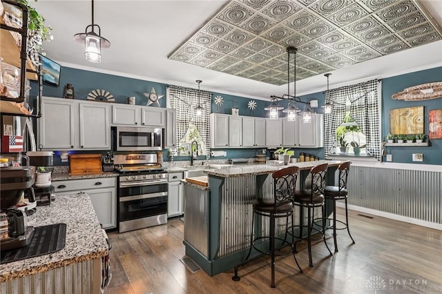 213 N Broadway St, Blanchester, OH 45107 - kitchen with appliances with stainless steel finishes, dark wood finished floors, light stone countertops, a breakfast bar area, and wainscoting