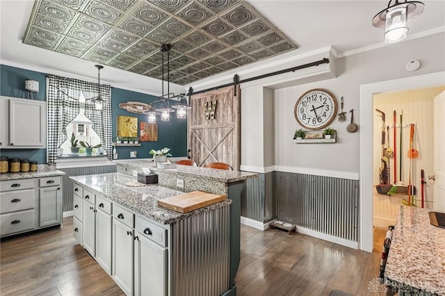 213 N Broadway St, Blanchester, OH 45107 - kitchen featuring dark wood-style flooring, a barn door, a kitchen island, decorative light fixtures, and light stone counters