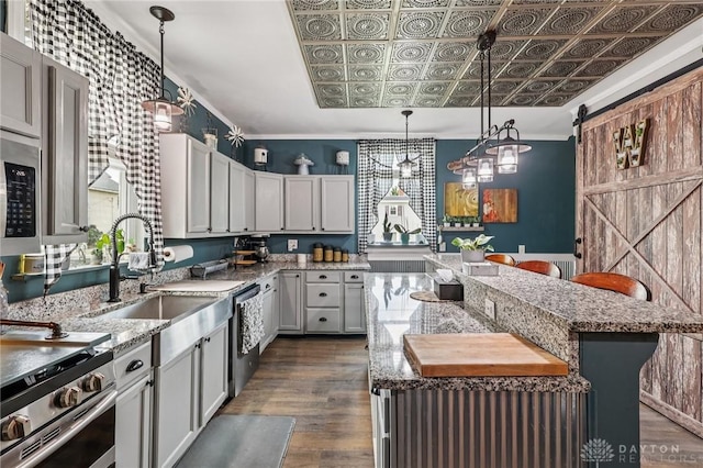 213 N Broadway St, Blanchester, OH 45107 - kitchen with appliances with stainless steel finishes, a kitchen island, an ornate ceiling, a barn door, and dark wood-style flooring