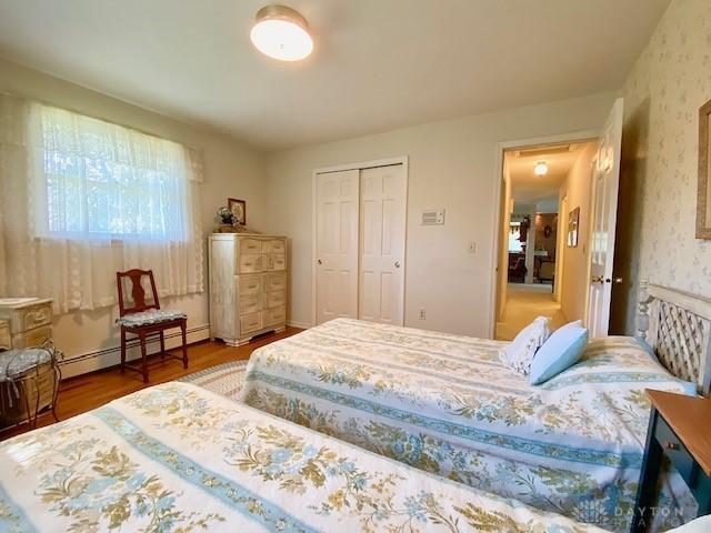 9476 Sheehan Rd, Dayton, OH 45458 - bedroom with a baseboard radiator, wood finished floors, a closet, and wallpapered walls