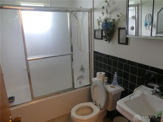 3784 Cheyenne Trl, New Jasper Twp, OH 45335 - bathroom featuring tile walls, shower / bath combination with glass door, and wainscoting
