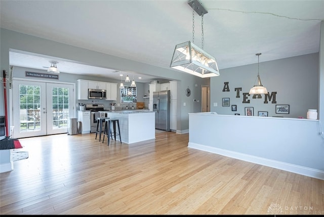 7143 S State Route 123, Blanchester, OH 45107 - kitchen with stainless steel appliances, light wood-style floors, white cabinetry, and french doors