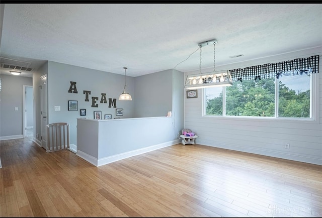 7143 S State Route 123, Blanchester, OH 45107 - empty room with a textured ceiling, light wood-style flooring, and wooden walls