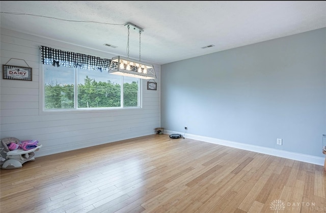7143 S State Route 123, Blanchester, OH 45107 - unfurnished dining area with light wood-style flooring, wooden walls, and a textured ceiling