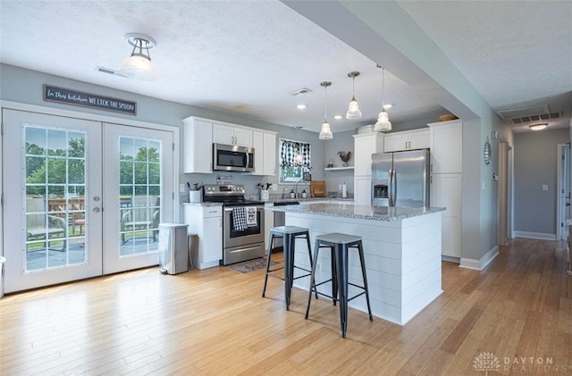 7143 S State Route 123, Blanchester, OH 45107 - kitchen featuring appliances with stainless steel finishes, light wood-style floors, a textured ceiling, french doors, and white cabinets
