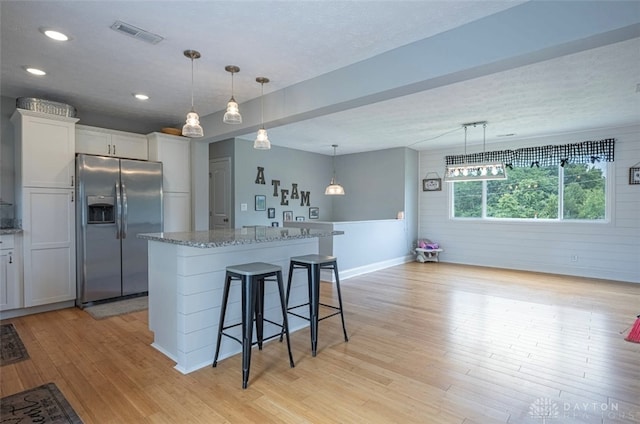 7143 S State Route 123, Blanchester, OH 45107 - kitchen featuring stainless steel fridge with ice dispenser, light wood-style floors, white cabinetry, a kitchen island, and light stone countertops