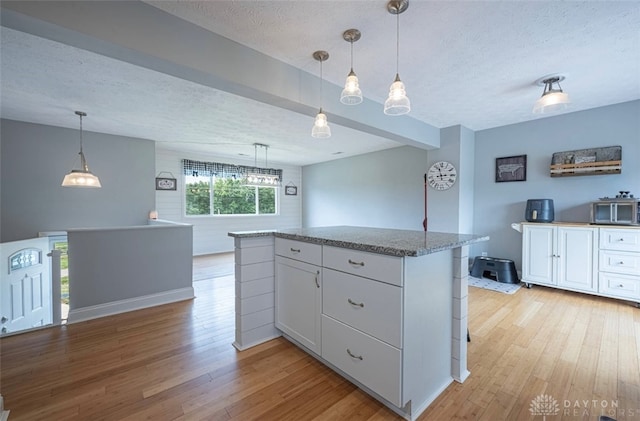 7143 S State Route 123, Blanchester, OH 45107 - kitchen featuring a textured ceiling, light wood finished floors, white cabinetry, light stone counters, and a kitchen island
